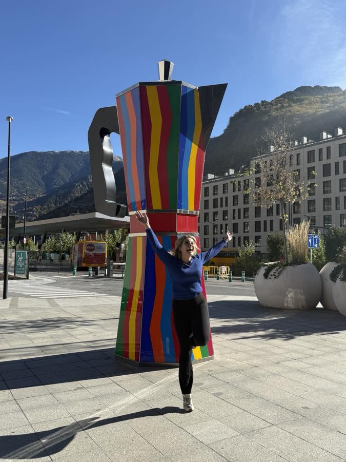 Cadia, founder of Cadia Catalyst, arms up in front of a giant colourful coffee pot